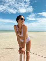 Top de bikini con aros, confeccionado en tela brillante color azul oscuro. Presenta breteles regulables con argollas decorativas y cierre mediante atado en la espalda.