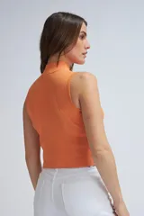Top tejido color naranja, con cuello halter y cierre frontal parcial con cremallera.