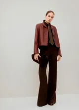 Chaqueta corta color bordó, de manga larga, con cuello camisero, bolsillos frontales con solapa y cierre de botones oscuros.