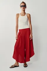 Pantalón fluido de tiro alto en color blanco, con pinzas delanteras, cintura elástica en la espalda y perneras anchas con aberturas laterales pronunciadas.