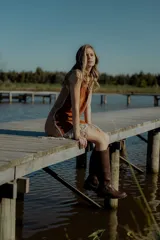 Vestido corto negro sin mangas, con escote en V y detalle de flecos en el ruedo. Presenta bordados en color blanco en el escote, los bolsillos y el centro del vestido.