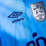 Camiseta de fútbol Umbro del Club Nacional de Football, Edición 26, color celeste con detalles en azul marino y blanco. Presenta escudo del club, logo de Umbro y sponsor Antel en el frente.