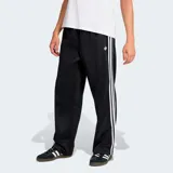 Pantalón deportivo Adidas Originals de corte holgado, color negro con las icónicas tres tiras blancas laterales y logo del trifolio bordado en la pierna.