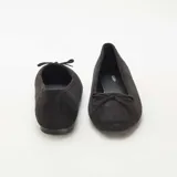 Bailarinas de mujer en color negro, confeccionadas en material tipo antelina con acabado suave. Presentan un diseño clásico de punta redondeada y un pequeño lazo decorativo en la parte frontal.