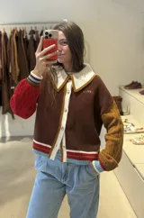 Cardigan de punto con diseño multicolor, cuello estilo polo en color crema, cierre frontal con botones y mangas de diferente color con textura de ochos.