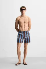 Short de baño confeccionado en tejido técnico con diseño de rayas verticales en tonos azul, marrón y beige. Cuenta con cintura elástica ajustable con cordón, bolsillos laterales y forro interior.