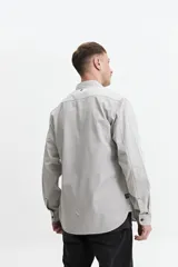 Camisa manga larga color verde oliva, corte slim fit, con cartera abotonada, dos bolsillos frontales con botón y confeccionada en 100% algodón.