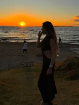 Vestido midi negro con cuello halter y aberturas laterales en la cintura.