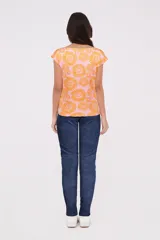 Remera de manga corta color rosa con estampado de flores naranjas, cuello redondo y corte holgado.