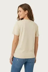 Remera de manga corta color beige, confeccionada en 100% algodón, con cuello redondo y estampa frontal con texto en tonos rosados.