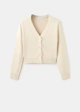 Cardigan de punto color beige con escote en V y cierre frontal con pequeños lazos del mismo tejido.