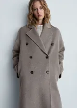 Abrigo largo de diseño oversize confeccionado en tejido con mezcla de lana. Presenta cuello con solapas de muesca, cierre frontal de doble botonadura y hombros caídos. Cuenta con dos bolsillos laterales y abertura posterior en el bajo.