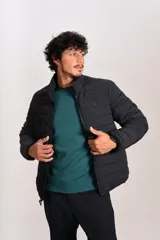 Campera acolchada negra con cierre frontal, cuello alto y diseño de costuras horizontales. Presenta un ajuste entallado y tejido exterior resistente al agua.