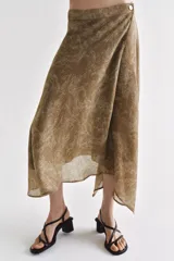 Falda midi de tiro alto y diseño asimétrico con cierre frontal cruzado y botón decorativo. Presenta una textura rústica con estampado sutil y forro interior marrón.