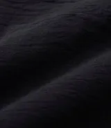 Blusa de manga corta color beige, confeccionada en tela texturizada. Presenta cuello redondo con detalle de pespuntes y cierre trasero con botón en forma de lágrima.