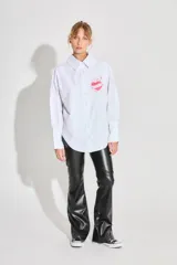 Pantalón semi oxford de ecocuero negro, tiro alto y cierre metálico lateral. Presenta un recorte arriba de la rodilla.