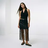 Falda midi negra transparente con bordados geométricos y ornamentales, de corte recto.