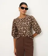 Blusa de viscolino con estampado animal print de leopardo, cuello redondo, mangas largas abullonadas y cierre frontal oculto.