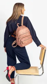 Mochila color marrón claro de símil cuero con bolsillos frontales con cierre. Tiene asa de mano rígida y correas regulables.