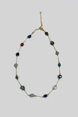 Collar corto de cadena dorada con piedras naturales irregulares de distintos colores distribuidas a lo largo de la pieza.