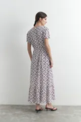 Maxi vestido blanco con estampado floral en tonos violeta, de manga corta y corte evasé.