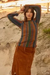 Sweater de lana de cordero con cuello a la base y manga larga. Presenta un diseño de franjas verticales combinando tejido de punto con detalles en crochet y cintas de lúrex brillante.