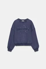 Sudadera de cuello redondo y manga larga con efecto lavado. Presenta texto bordado en el frente y aplicación de tachas decorativas. Posee puños y ruedo con acabado en rib.