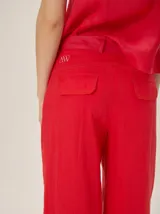 Pantalón sastrero de corte ancho, color beige con rayas verticales blancas y detalles de costuras pespunteadas.