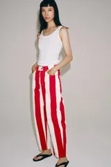 Jeans de tiro medio y corte tapered, con diseño de rayas verticales a contraste en color rojo y blanco. Cuenta con trabillas en la cintura, cinco bolsillos y cierre frontal con cremallera y botón metálico.