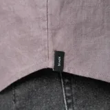 Camisa de lino color gris topo, de corte clásico, con cuello abotonado, manga larga y bolsillo en el pecho.