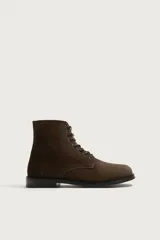 Bota de caña baja tipo derby confeccionada en piel con acabado serraje en color marrón, con cordones oscuros y suela con ligero tacón.