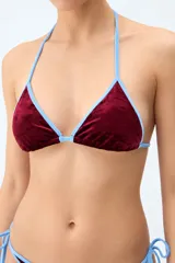 Top de bikini de terciopelo bordó con ribetes en color celeste, diseño triangular y tirantes finos para atar al cuello y espalda.