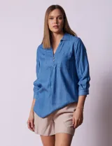Blusa celeste de lyocell con cuello con solapa, escote en V y cierre con botones. Tiene un bolsillo en el pecho, mangas 3/4 con puño y botón.