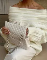 Buzo tejido de punto color crudo con diseño off-shoulder, textura acanalada y calce relajado.