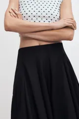 Falda midi de tiro alto en color verde militar, con diseño acampanado y cintura elástica. Presenta costuras verticales que definen su estructura y cierre lateral con cremallera oculta.
