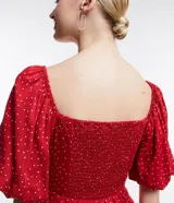 Vestido corto rojo con lunares blancos, escote cuadrado, mangas cortas abullonadas y abertura lateral en la falda.