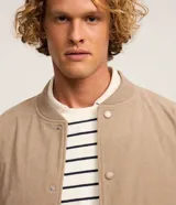 Campera bomber masculina de terciopelo cotelé color beige, con cuello redondo, mangas largas, cierre frontal de botones forrados, bolsillos laterales y terminaciones de elástico en puños y cintura.