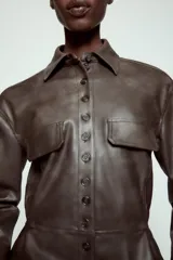 Cazadora de efecto piel con cuello solapa, manga larga y cierre frontal con botones. Presenta falsos bolsillos con solapa en el delantero y bajo con acabado peplum.