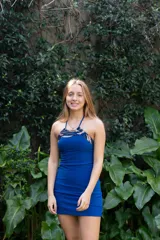 Vestido corto azul con escote halter y espalda descubierta. Presenta detalles de encaje negro en el escote y los laterales.