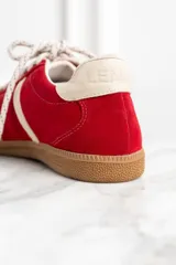 Zapatillas rojas de gamuza con detalles en cuero blanco y suela de goma color caramelo.