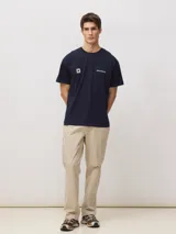Camiseta de manga corta en color azul marino, con cuello redondo y corte clásico. Presenta un pequeño estampado en el pecho que incluye el logo de la marca y una cruz dentro de un cuadrado.
