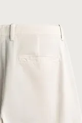 Pantalón cargo relaxed fit de color blanco, confeccionado en tejido de algodón. Presenta bolsillos de plastrón con solapa en las perneras y cierre frontal con cremallera y botón.