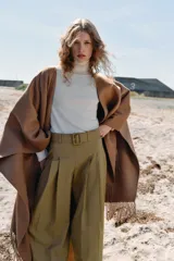 Jersey de punto liso en color beige, con cuello alto y manga larga con detalle de botones metálicos en los puños.