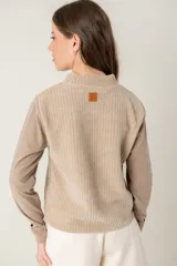Polera de manga larga con diseño combinado, presentando un panel frontal de tejido acanalado en tono beige y mangas de tela lisa en tono arena. Posee cuello alto y corte recto.