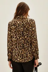 Camisa de corte clásico con cuello camisero y cierre frontal de botones, confeccionada en tela fluida con estampado animal print de leopardo.