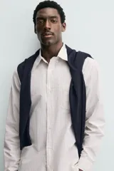 Camisa de corte regular fit confeccionada en tejido de algodón con estampado de cuadros pequeños. Presenta cuello abotonado, manga larga con puños abotonados, bolsillo de plastrón en el pecho y cierre frontal con botones.