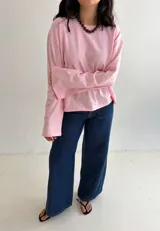 Remera oversize rosada de manga larga y ancha, con cuello redondo y diseño holgado.