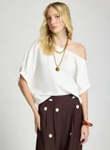 Blusa blanca con diseño de hombro caído, manga corta abullonada y corte holgado.