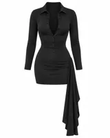 Vestido corto camisero negro de manga larga, con cuello y escote profundo con botones. Presenta drapeado en la cadera con caída asimétrica lateral y diseño elastizado que marca la silueta.