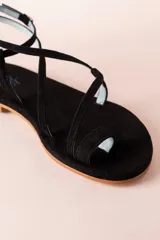 Sandalias negras de tiras finas, con suela plana y cierre con hebilla en el tobillo.